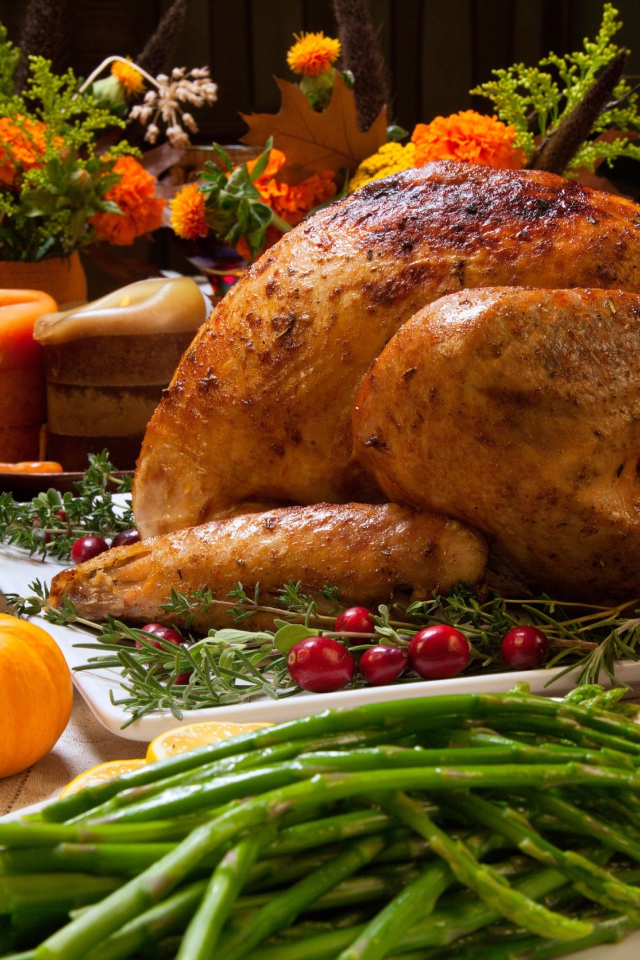 Аппетитная запеченная курица с зеленой спаржей и угощениями на праздничном столе