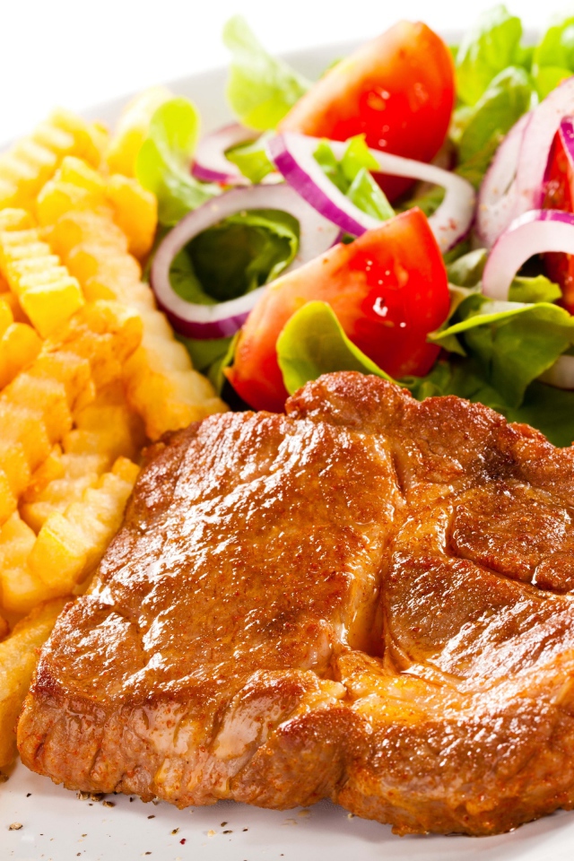 Аппетитная отбивная на тарелке с картофелем фри и салатом