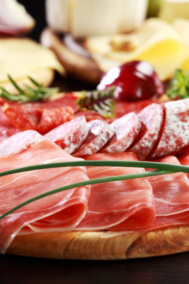 Аппетитная мясная нарезка на деревянной доске с зеленым луком