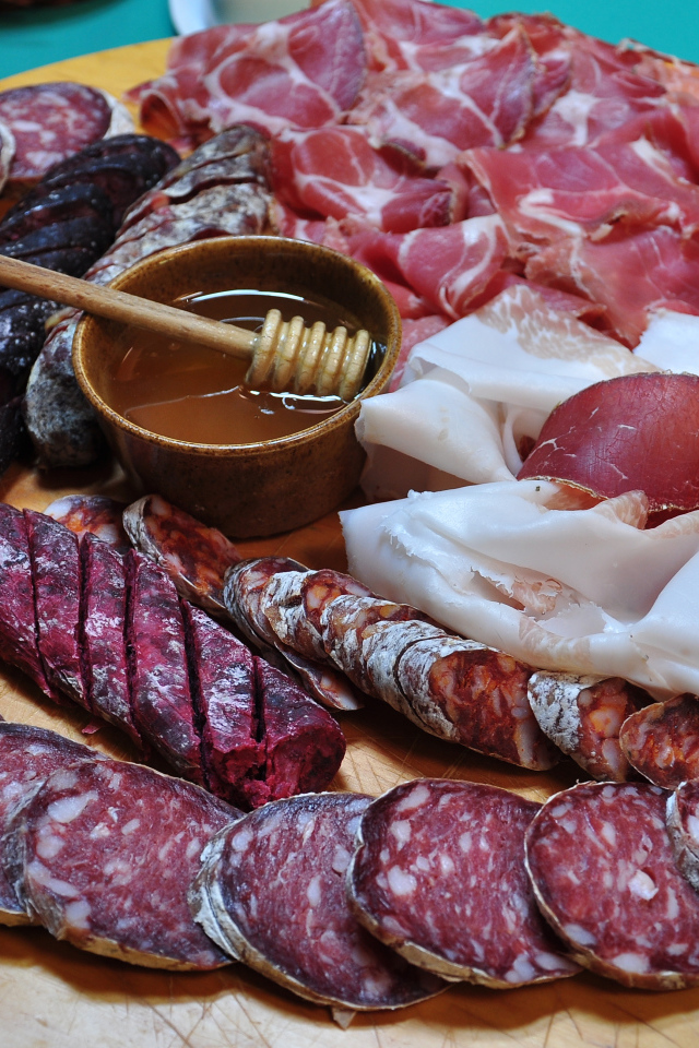 Аппетитная мясная нарезка на разделочной доске с медом