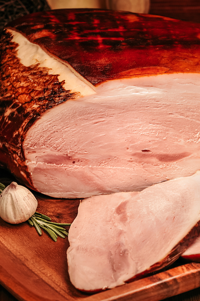 Аппетитный кусок ветчины с перцем и чесноком на доске