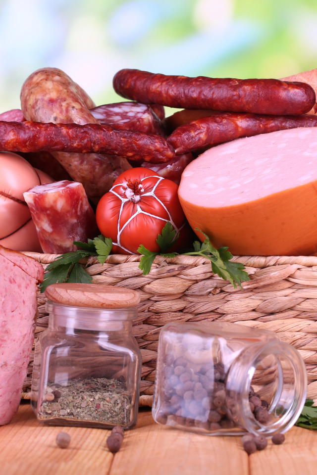 Аппетитная колбаса в корзине на столе со специями