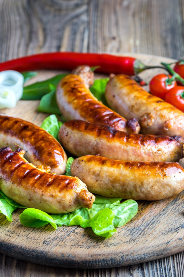 Сосиски барбекю с красным перцем и помидорами на разделочной доске