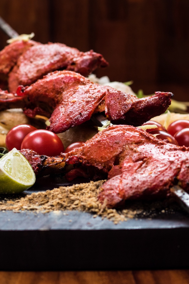 Курица жареная на шампурах на столе с овощами 