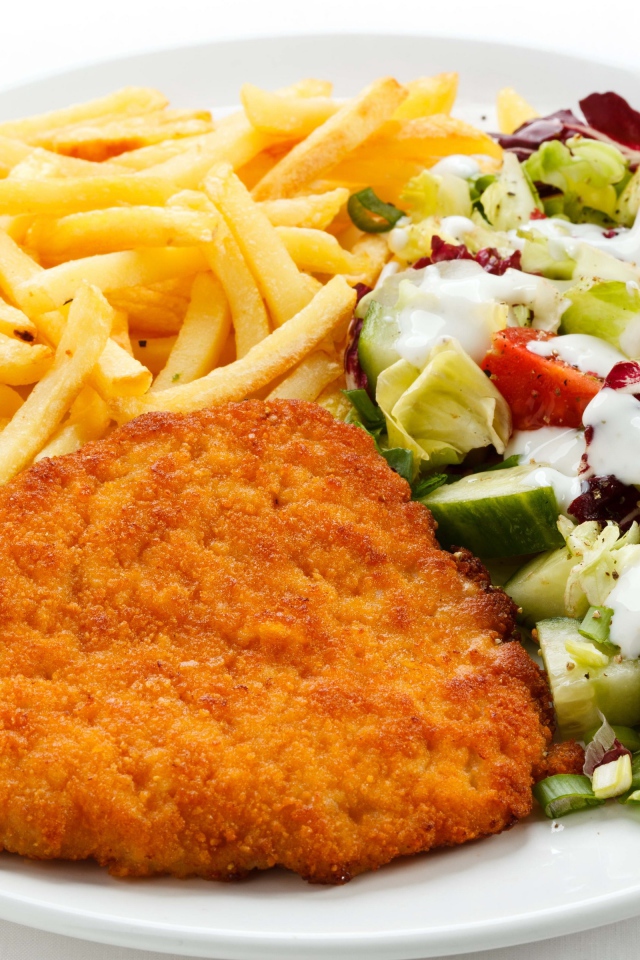 Отбивная на тарелке с картофелем фри и салатом