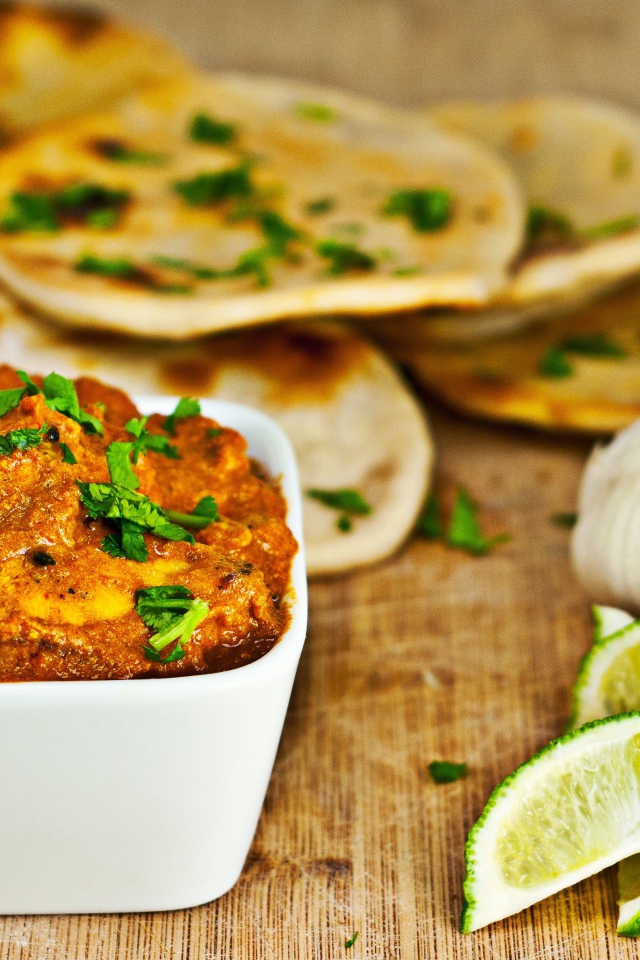 Мясное блюдо на столе с лепешками, кусочками лайма и чесноком