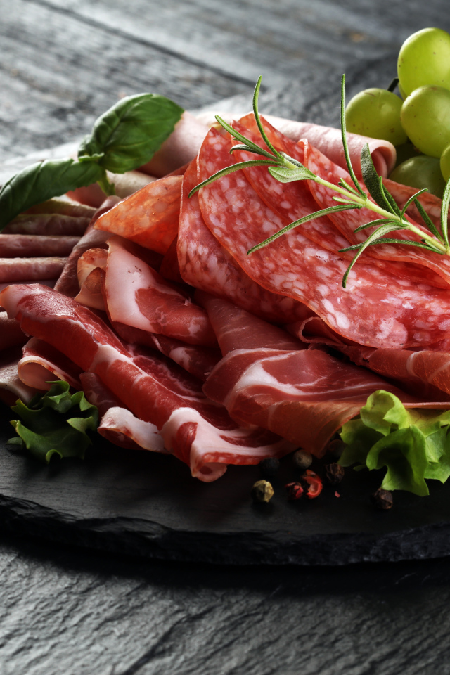 Мясная нарезка с листьями салата и белым виноградом 