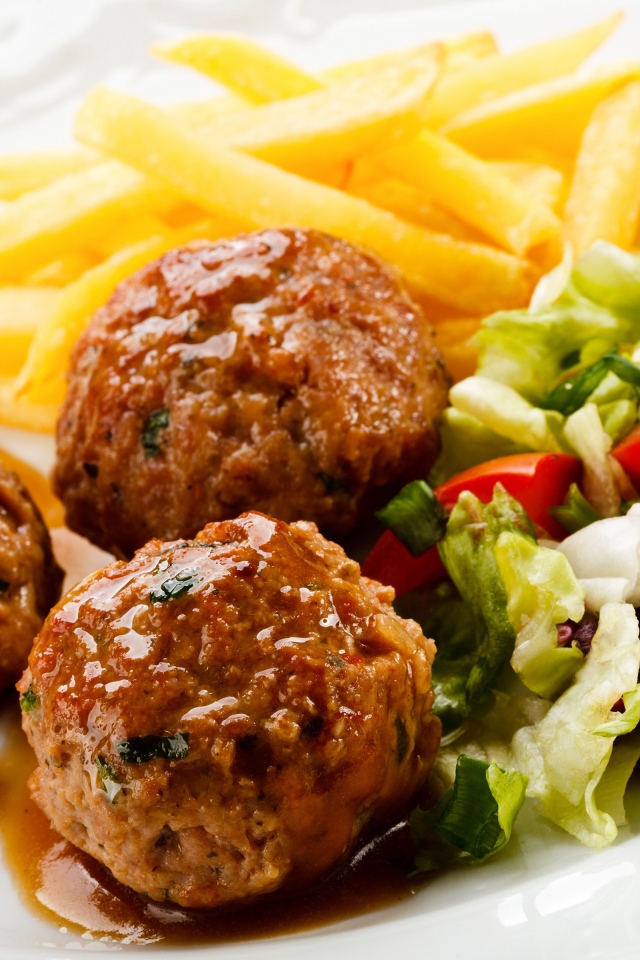 Тефтели с картофелем фри и салатом на белой тарелке 