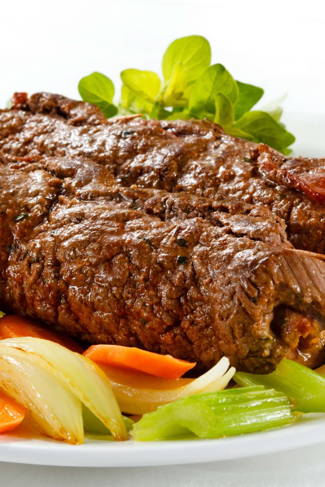 Свинина на тарелке с овощами на белом фоне