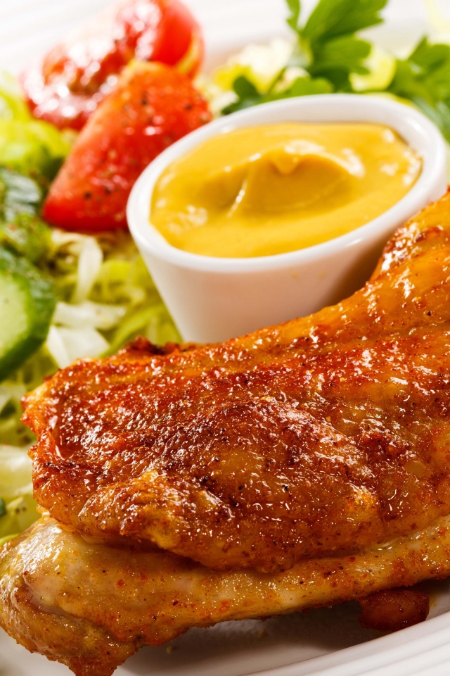 Жареная куриная ножка с овощами и соусом на тарелке