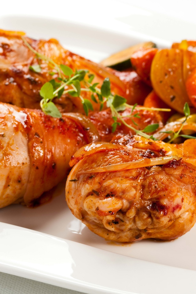 Жареные куриные ножки с овощами на белом фоне