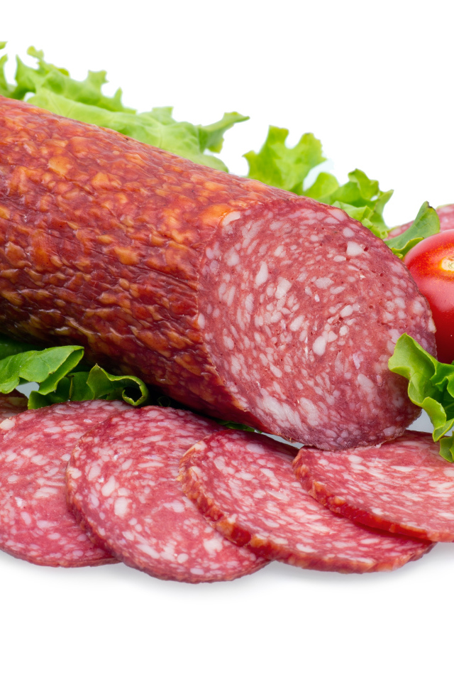 Колбаса с помидорами и зелеными листьями салата на белом фоне