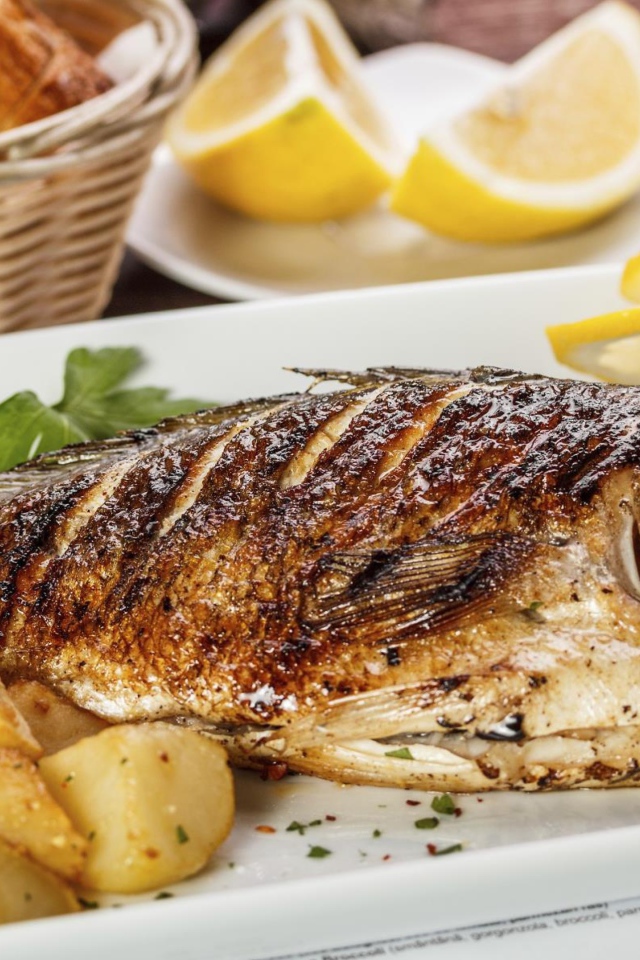 Запеченная рыба на тарелке с картофелем и лимоном 