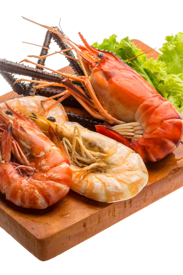 Вареные креветки с листьями салата на разделочной доске