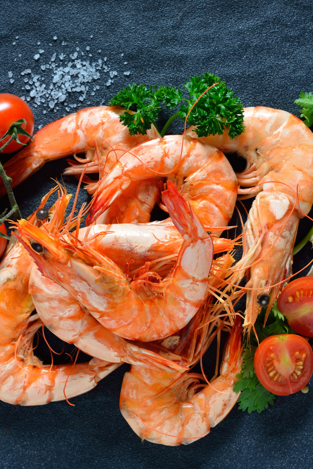 Вареные креветки на столе со специями и  помидорами 