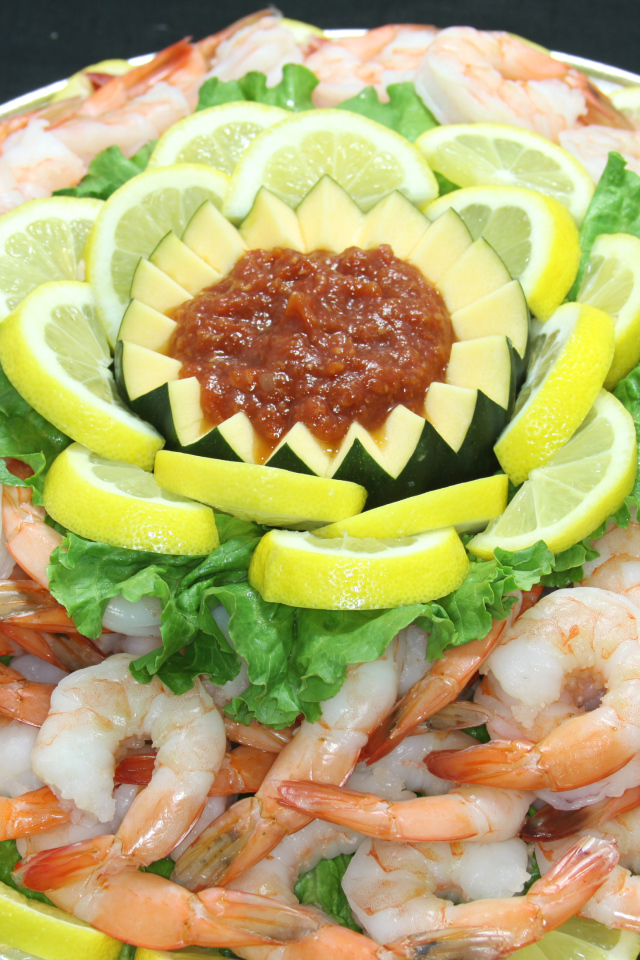 Вареные креветки с лимоном и соусом на большой тарелке