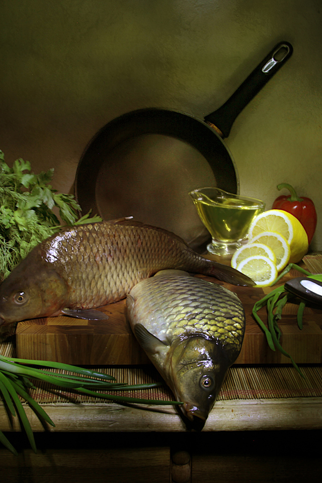 Сырая рыба на столе с зеленью, лимонами и луком 