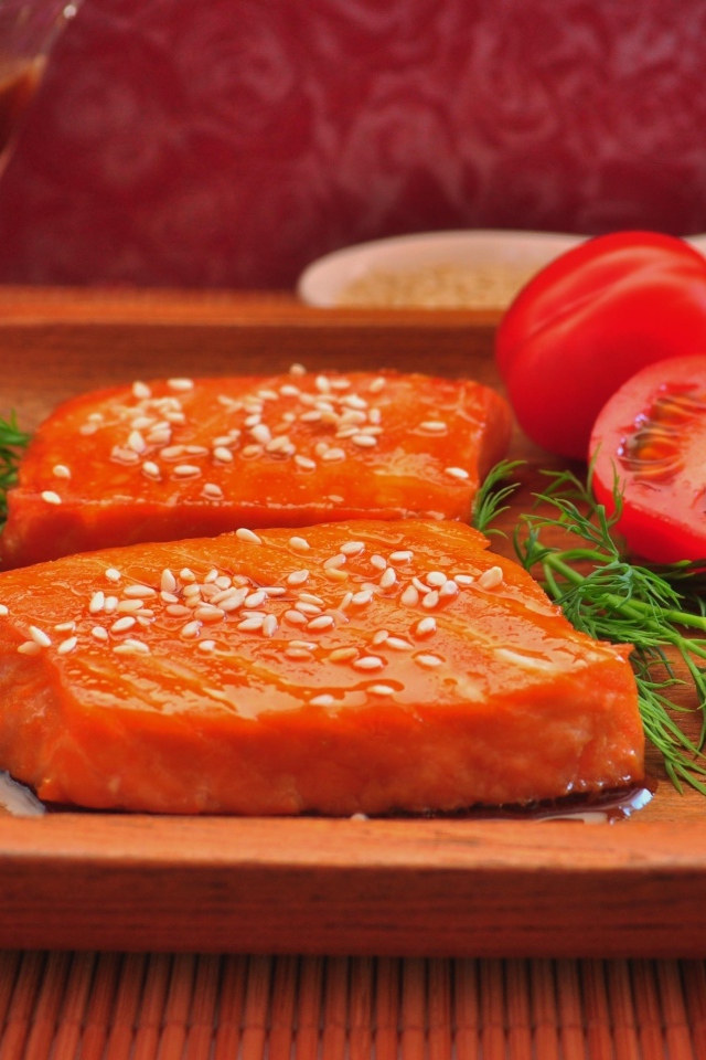 Красная рыба с кунжутом на тарелке с помидорами и укропом