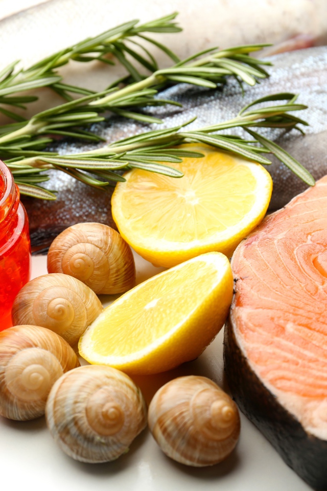 Красная рыба с улитками и красной икрой на столе с лимоном и базиликом