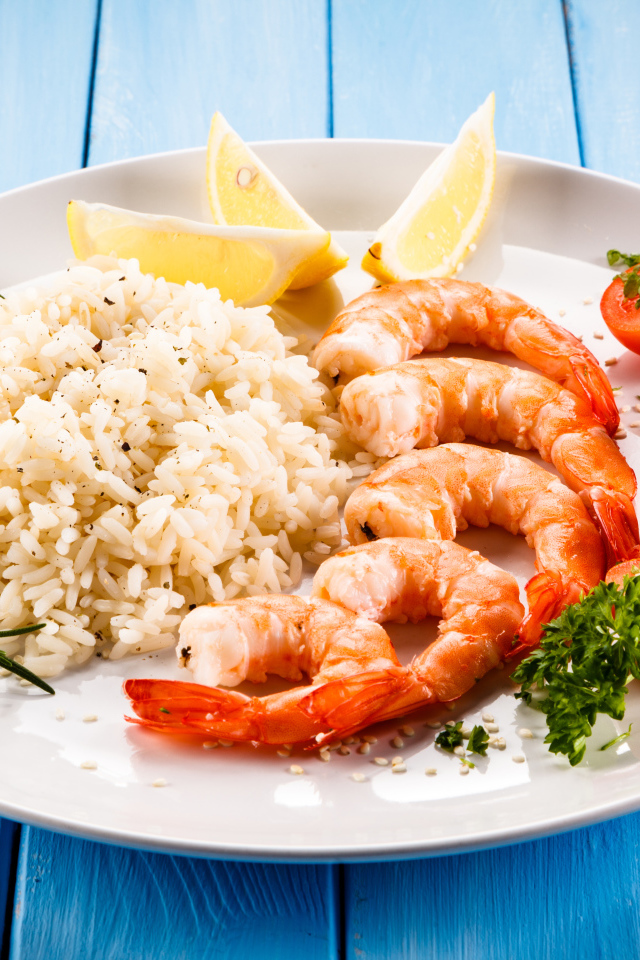 Креветки на тарелке с рисом, помидорами и лимоном