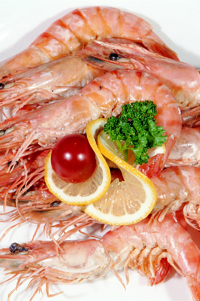 Креветки с лимоном и помидором на белой тарелке