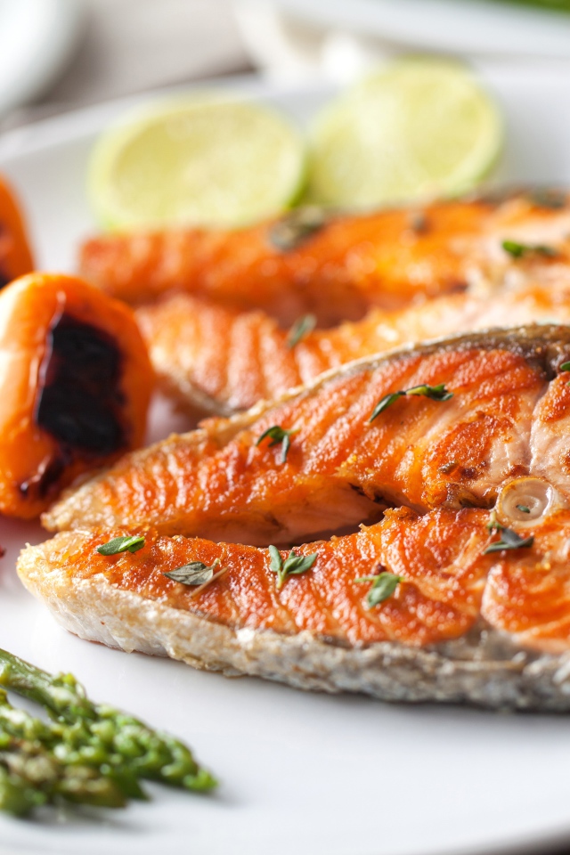 Куски жареной рыбы на тарелке со спаржей и жареным перцем 