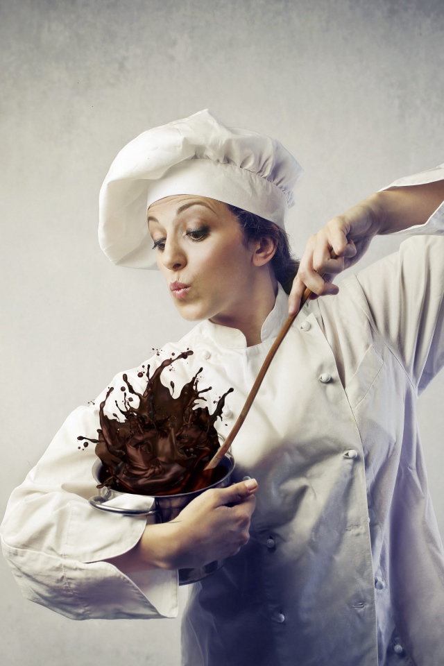 Женщина повар мешает шоколад в посуде на сером фоне