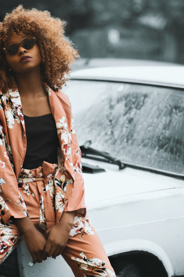 Красивая темнокожая девушка сидит на автомобиле 