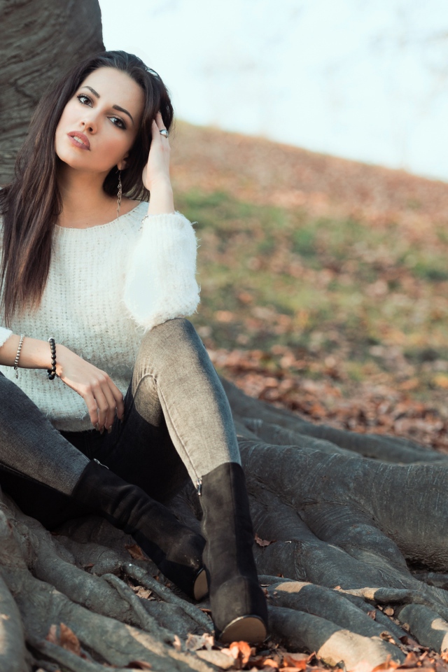 Красивая девушка сидит у дерева