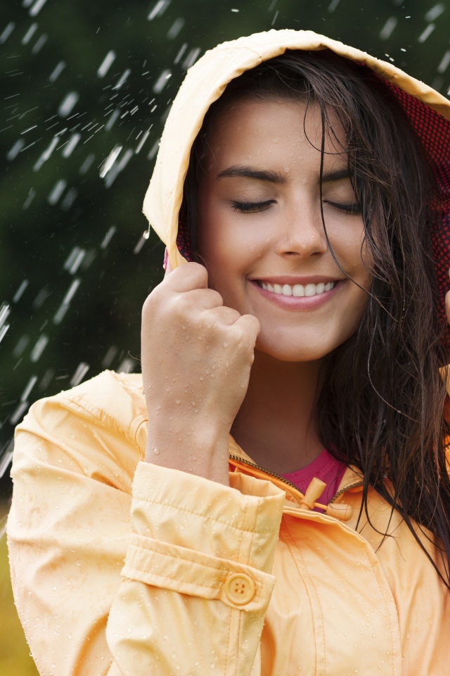 Красивая молодая девушка в желтом плаще стоит под дождем