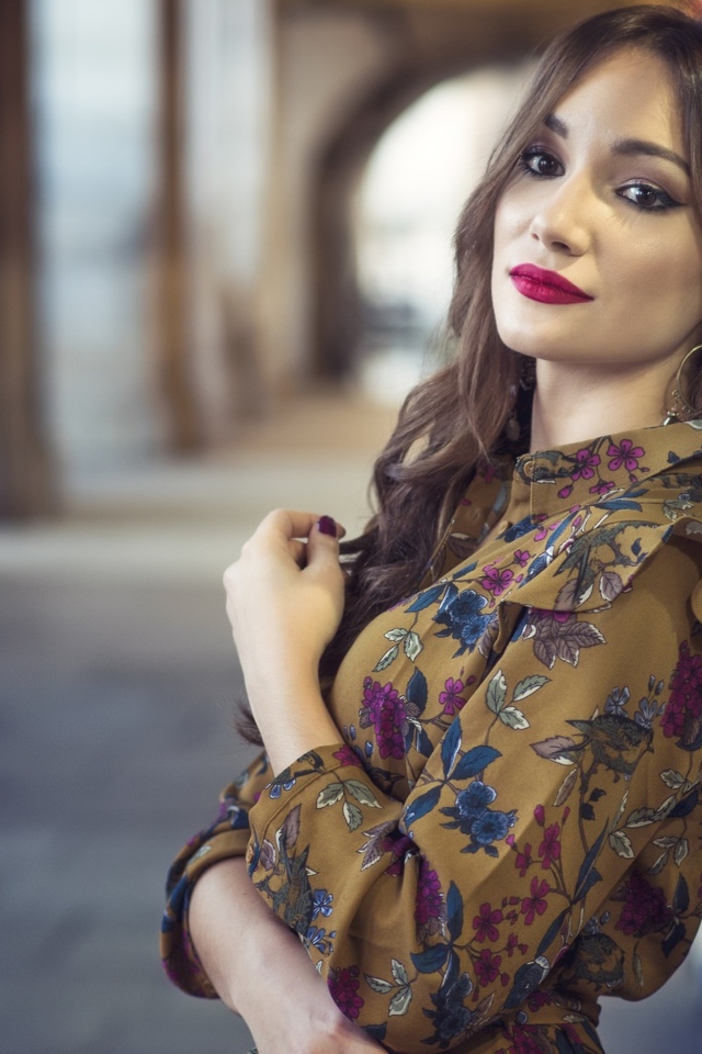 Девушка шатенка в красивом платье у стены