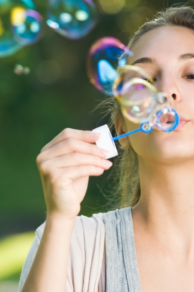 Милая молодая девушка пускает мыльные пузыри