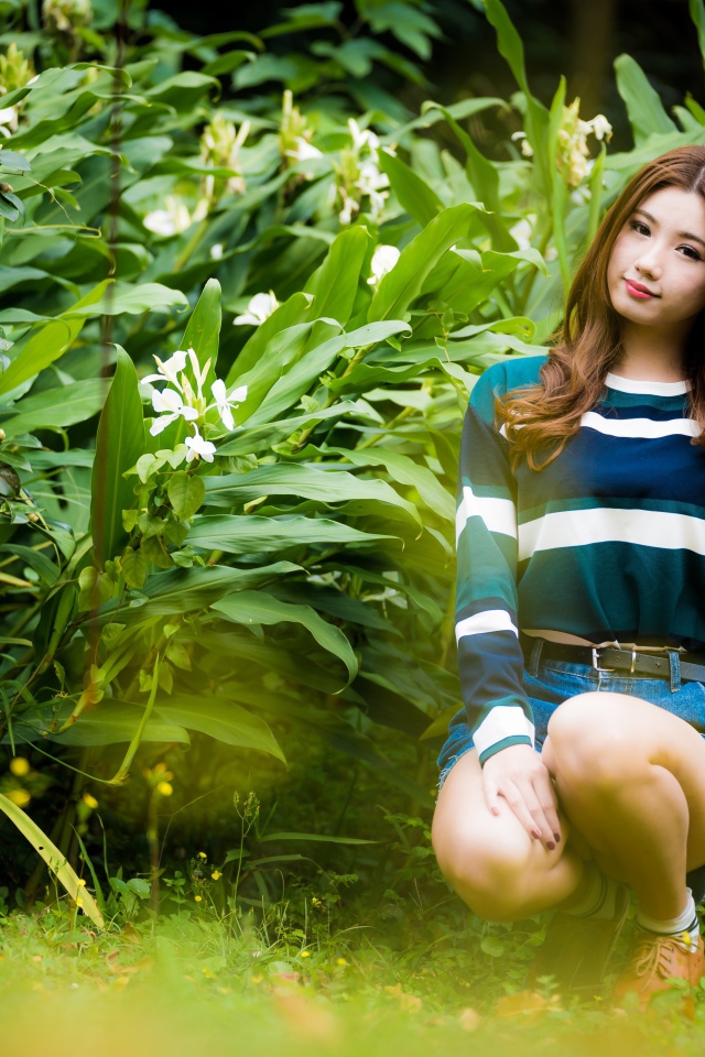 Молодая азиатка сидит в зеленых листьях 