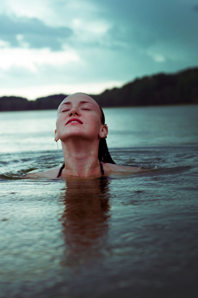 Молодая девушка купается в озере 