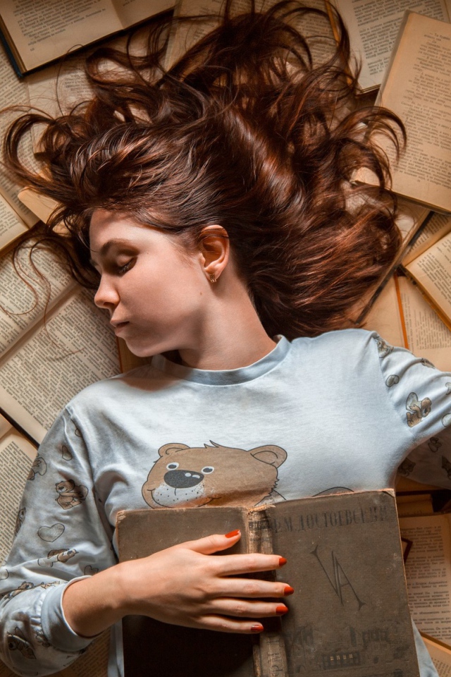 Молодая девушка спит на книгах