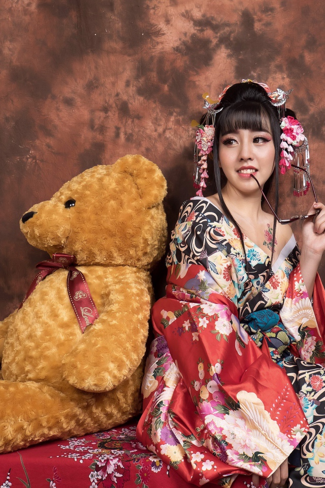 Девушка азиатка сидит с большим плюшевым медведем