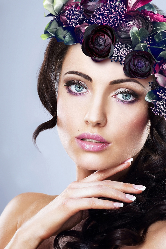 Красивая голубоглазая девушка с венком на голове на сером фоне