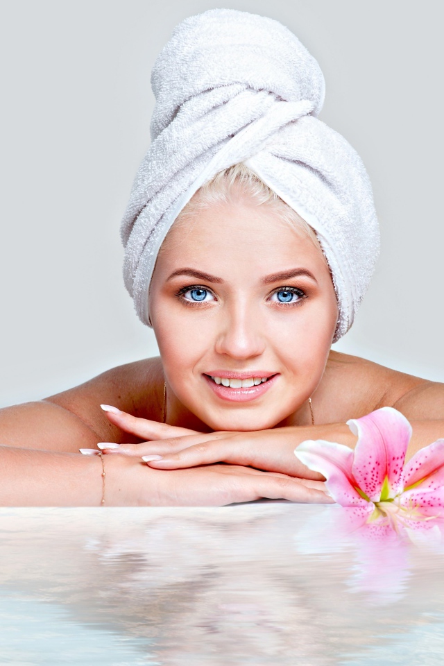 Красивая голубоглазая женщина в тюрбане с полотенца расслабляется в SPA