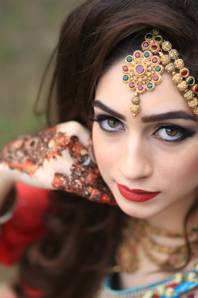 Красивая кареглазая девушка в индийском костюме с рисунками на руках 