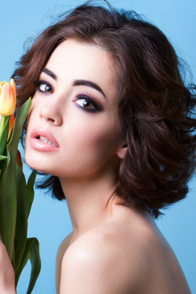 Красивая девушка брюнетка с букетом тюльпанов на голубом фоне