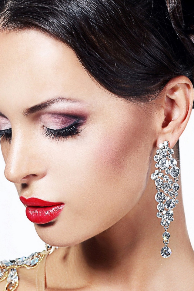 Красивая брюнетка в дорогих украшениях на белом фоне