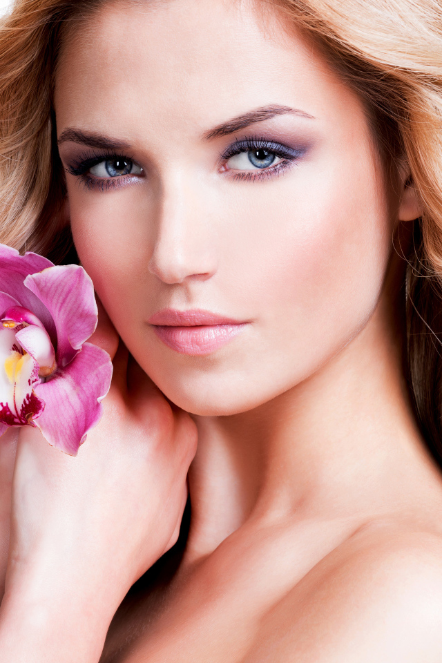 Красивая нежная блондинка с цветком орхидеи на белом фоне