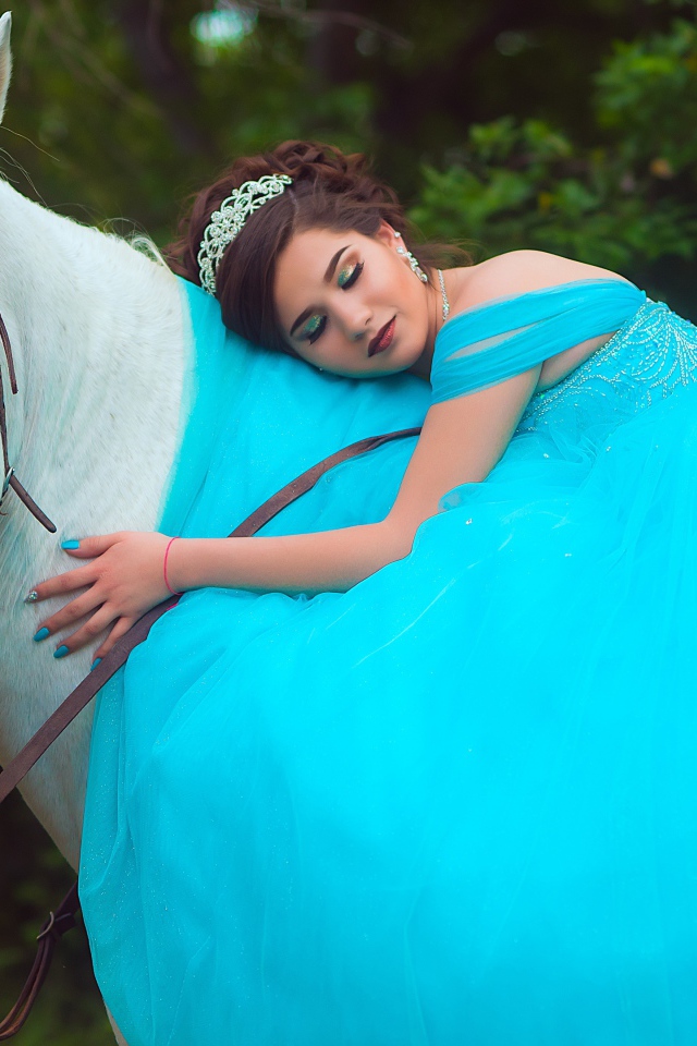 Красивая девушка в пышном голубом платье на лошади