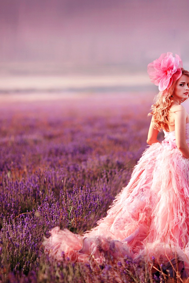 Красивая девушка в розовом платье гуляет по лавандовому полю