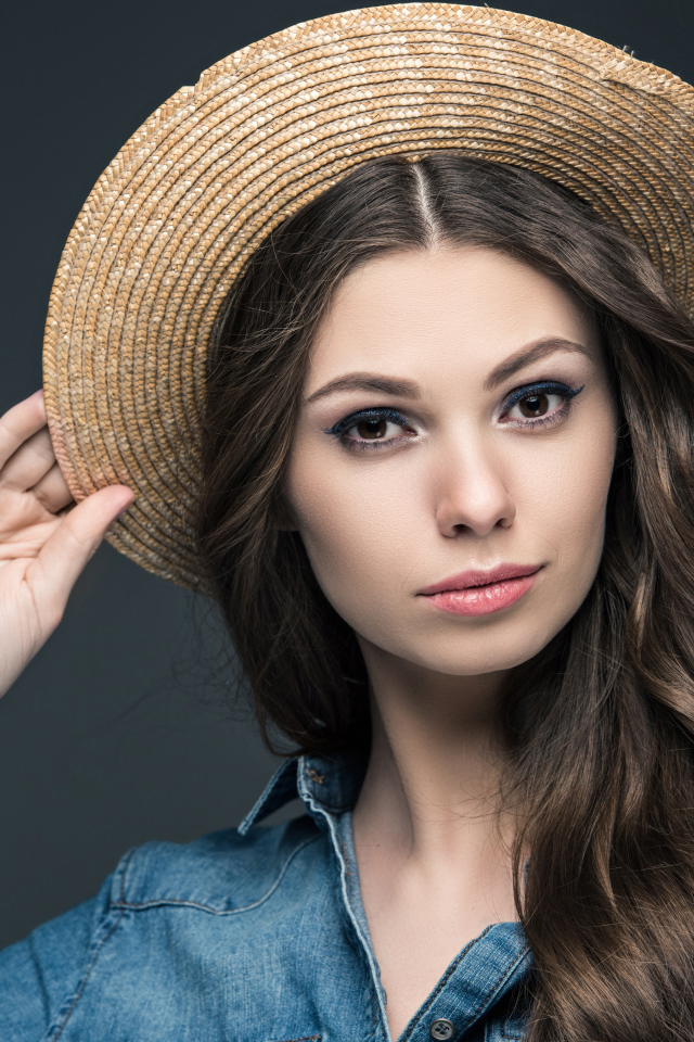 Красивая девушка в соломенной шляпе на сером фоне