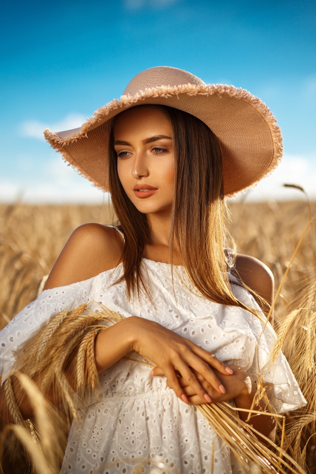 Красивая девушка в белом платье с колосьями пшеницы