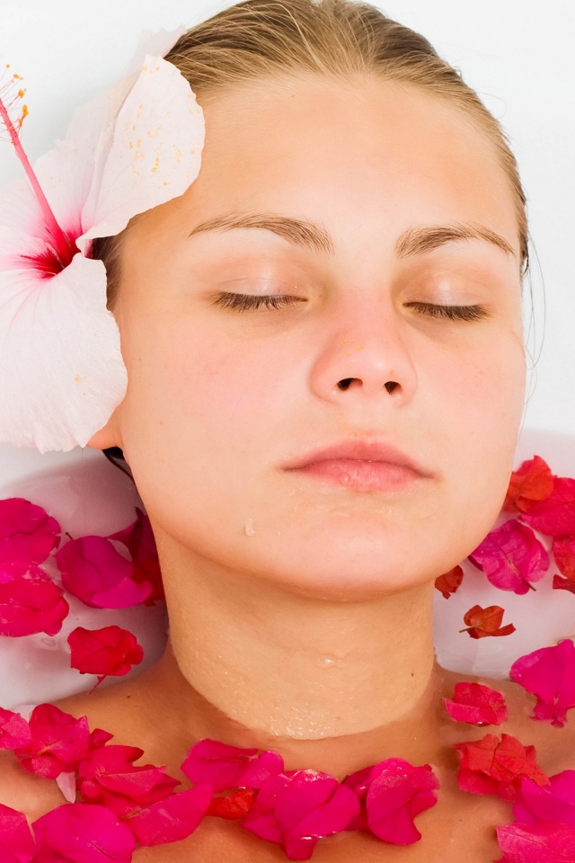 Красивая девушка в ванной с лепестками розы 