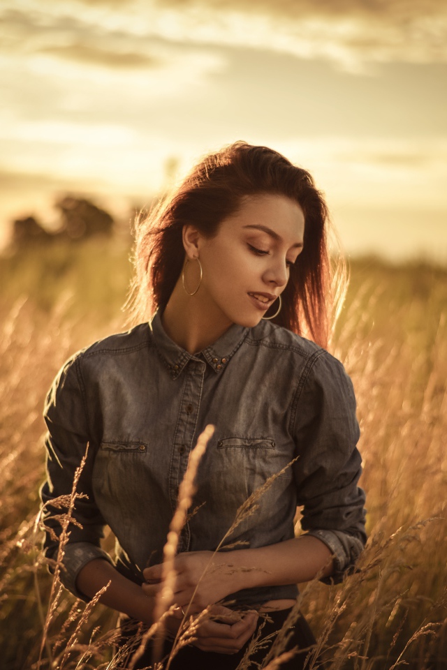 Красивая девушка на поле с колосками на фоне солнца