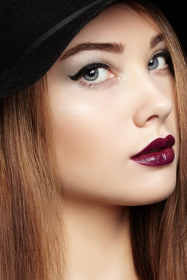 Красивая девушка с ярким макияжем в большой черной шляпе