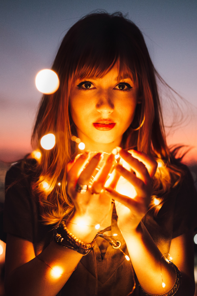 Красивая девушка с включенной гирляндой в руках 